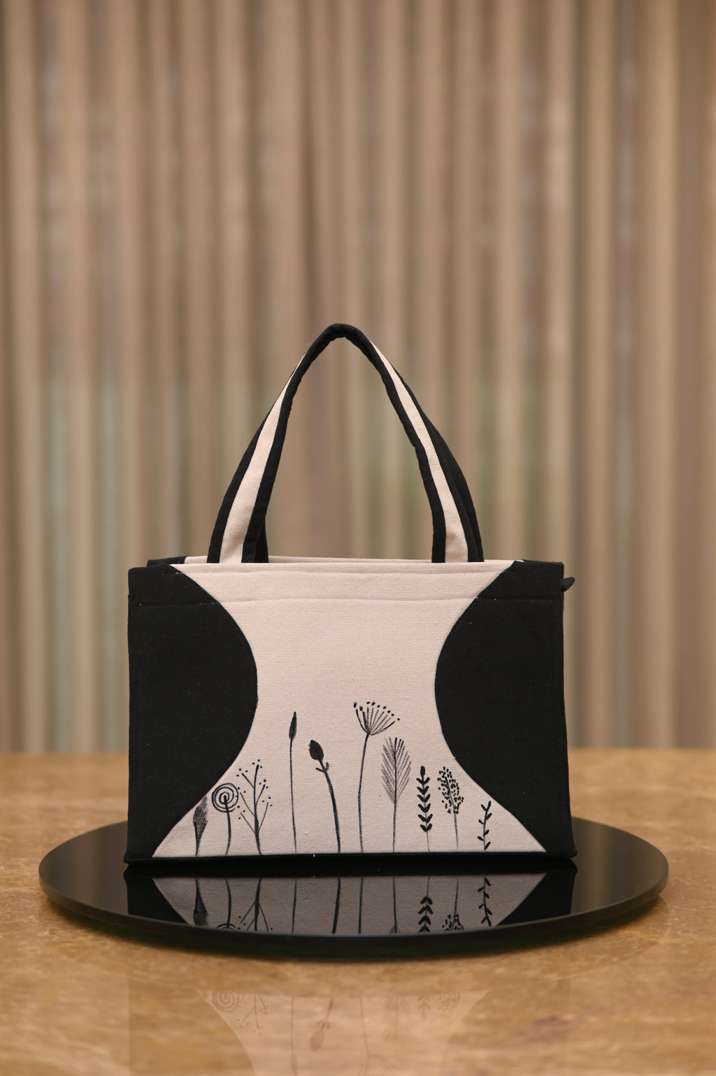 Black and white handbag with floral designs on a wooden surface