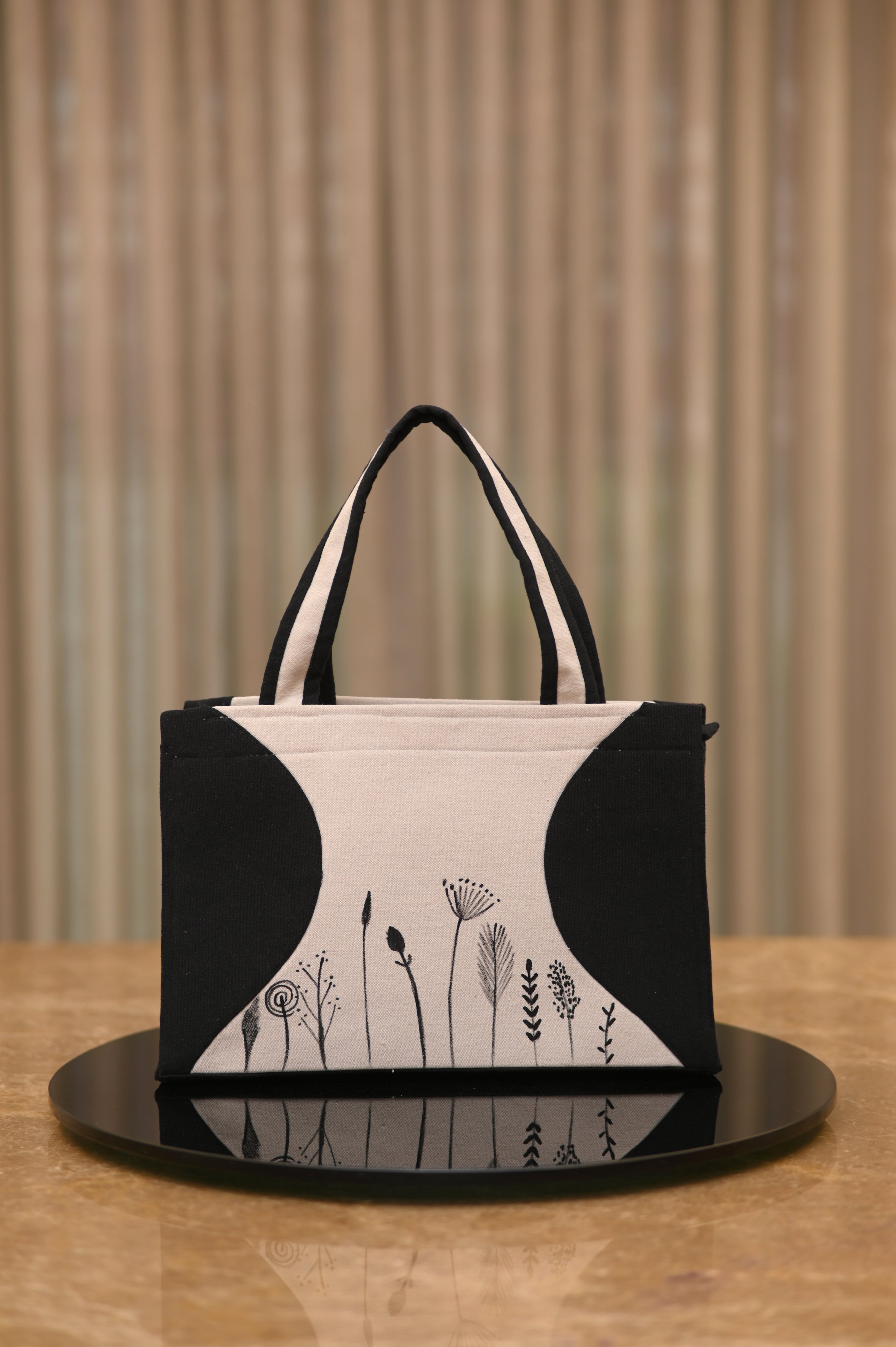 Black and white handbag with floral designs on a wooden surface